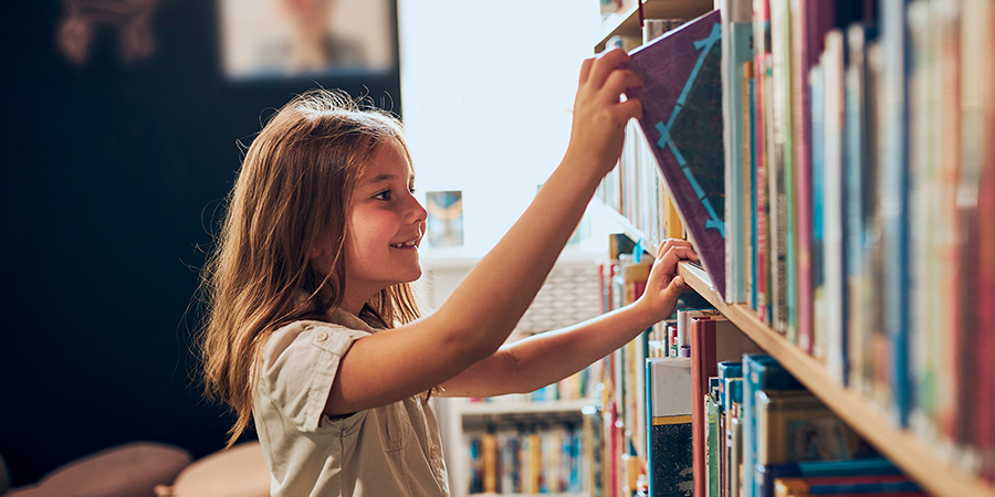 menina pegando livro na estande para leitura 